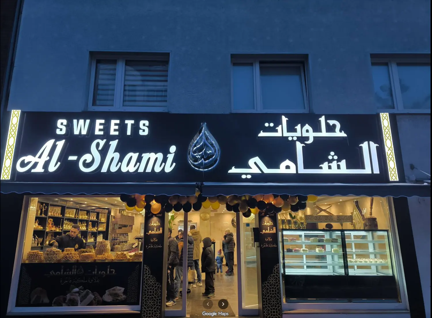 Beleuchtete Außenansicht von Al-Shami Sweets am Abend