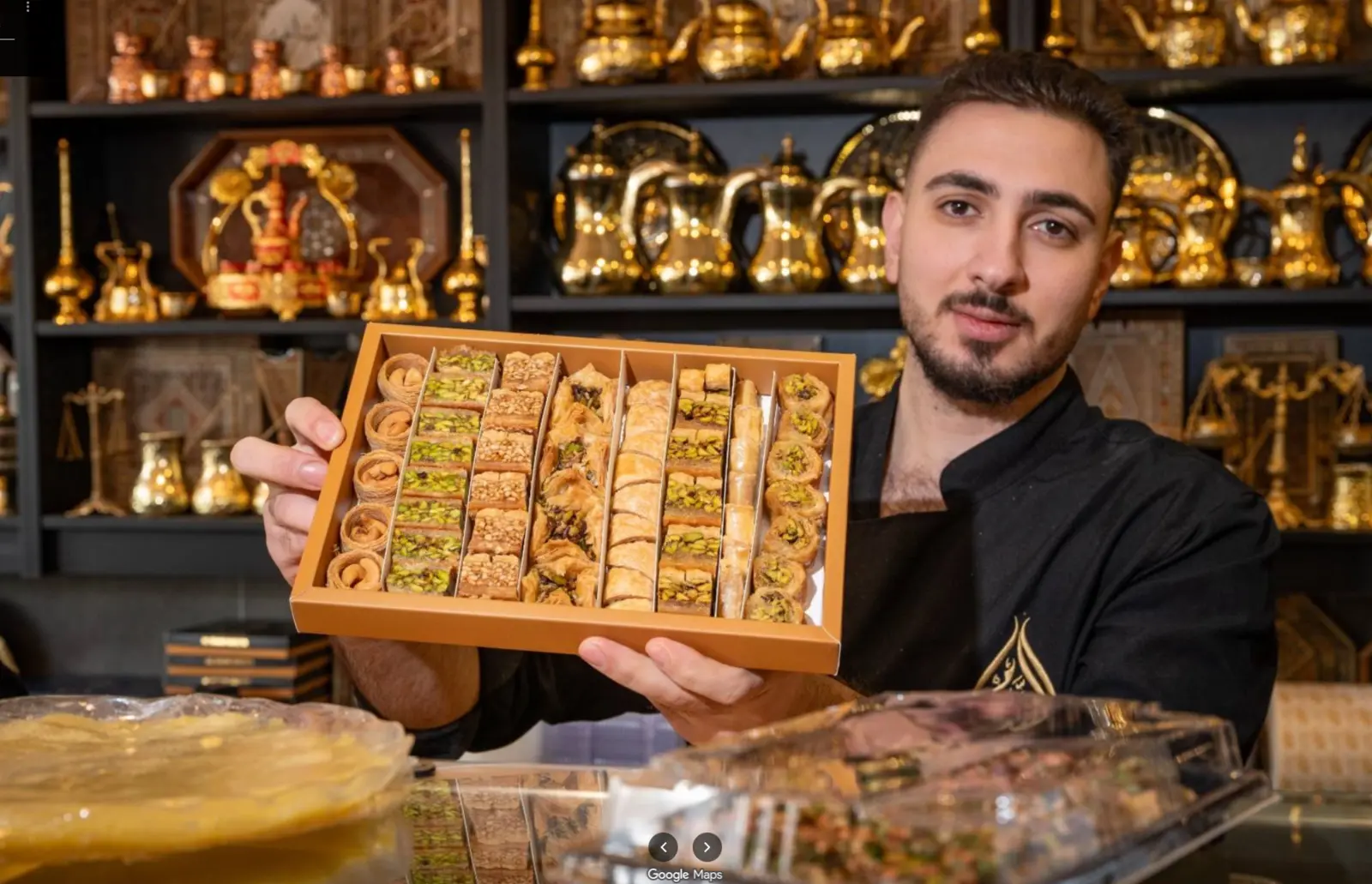 Eine Person präsentiert eine gemischte Auswahl orientalischer Süßwaren im Geschäft